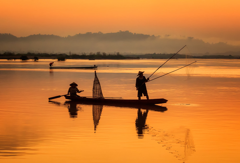 Fishermen casting a net from a traditional boat (Photo Credit : SantiPhotoSS)