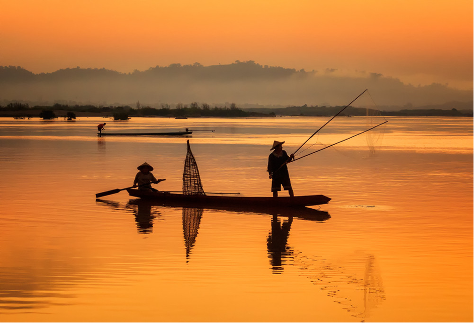 Fishermen casting a net from a traditional boat (Photo Credit : SantiPhotoSS)
