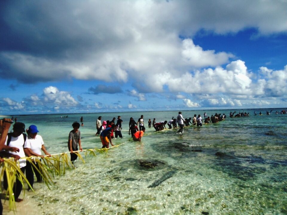 Customary elders and community members gathering on the shore in Maluku to conduct sacred rituals marking the opening (buka sasi) or closing (tutup sasi) of a protected marine zone (Photo Credit : The Guardian - Traditional Fisheries and Customary Law Archives)