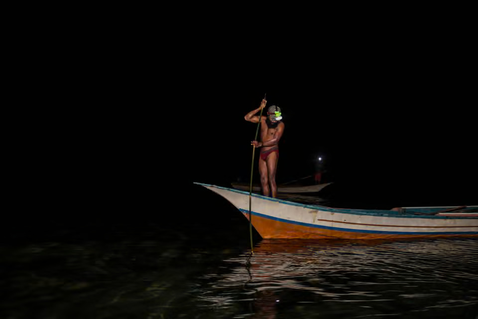 Mike Tison Mangar collects lobsters from the bow of a boat during the breaking of Sasi (Photo Credit : Garry Lotulung)
